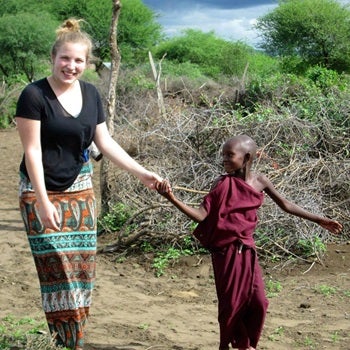 Nursing student holding hands with a kid in Africa